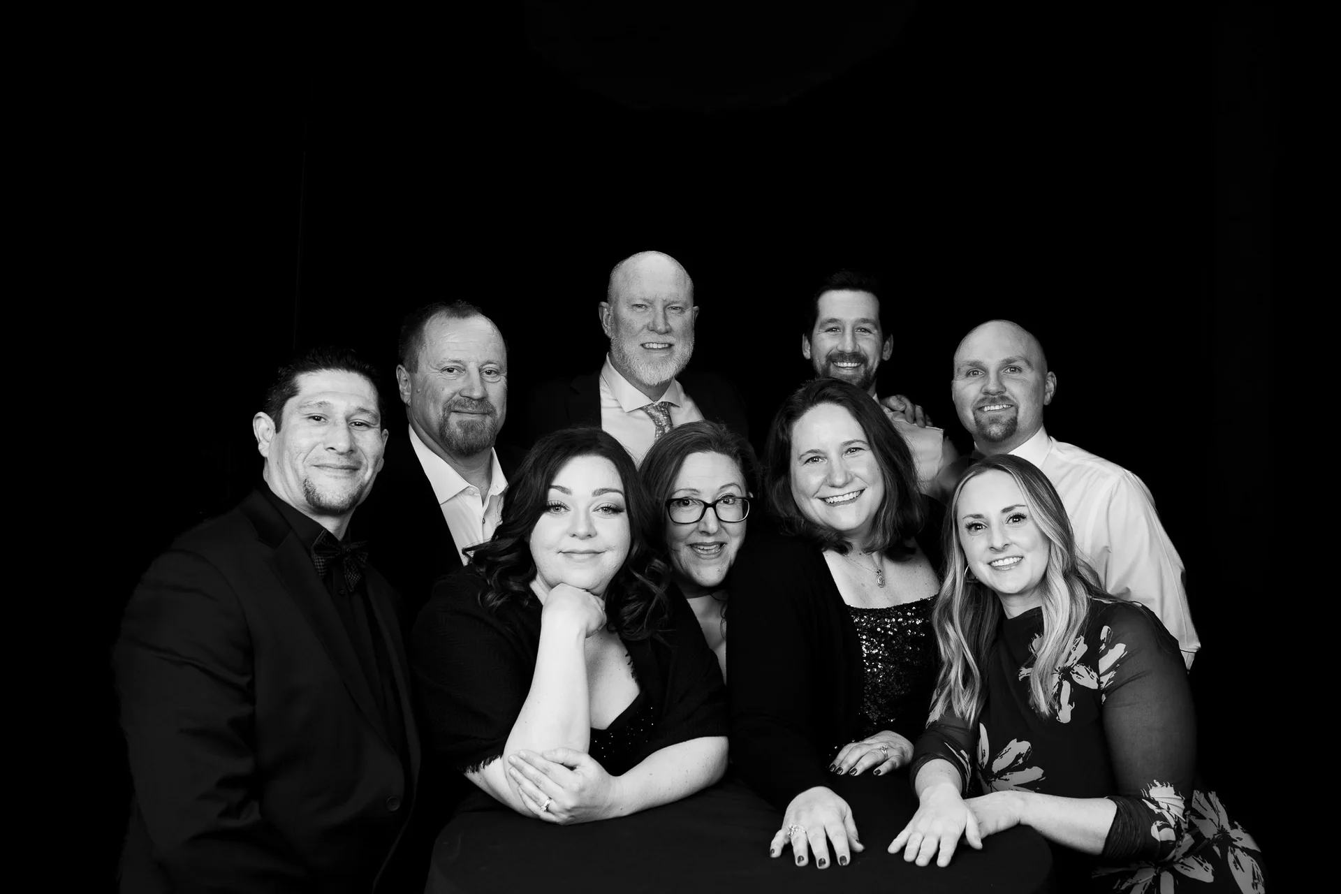 A group of colleagues pose together against a dark background.