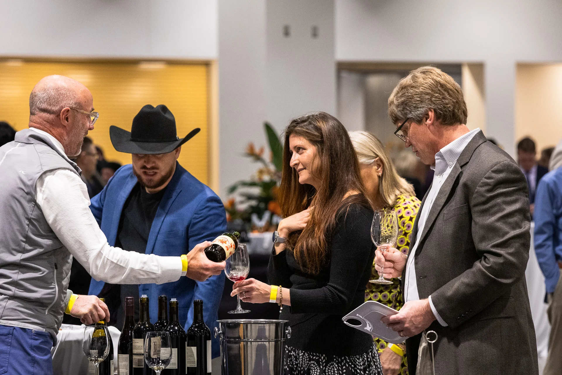 People gather at a tasting as one attendee pours a drink.